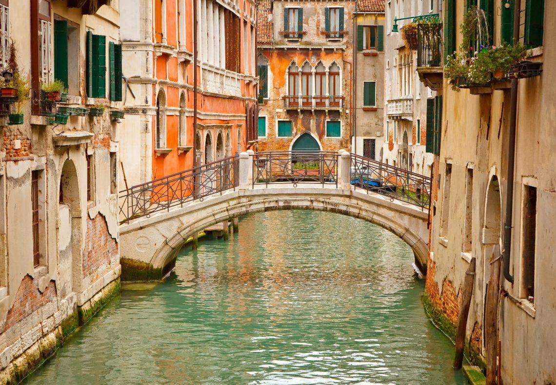 Canal pitoresco de Veneza com ponte.